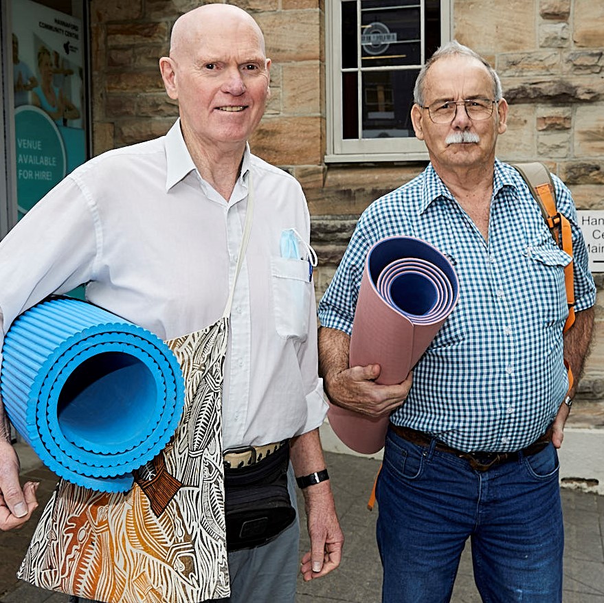 Two men standing holding yoga mats